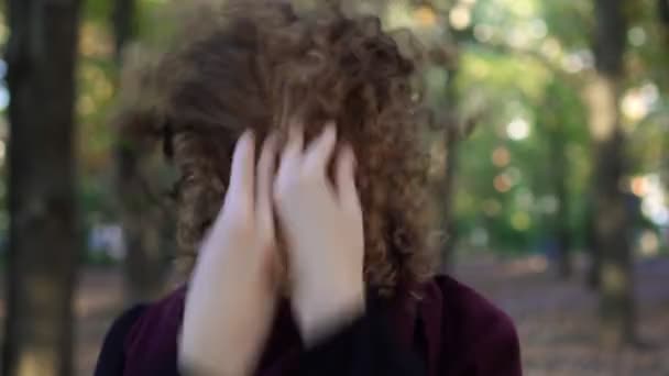 Portrait of a young beautiful woman with curly hair. Warm autumn, park. — Stock Video
