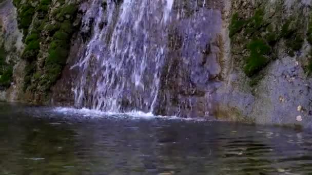 Bergwasserfall. ein schöner Wasserfall fließt die Klippe hinunter in den See. — Stockvideo