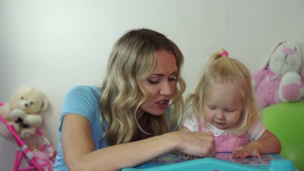 Mom and baby are playing at the table in the room. — Stock Video