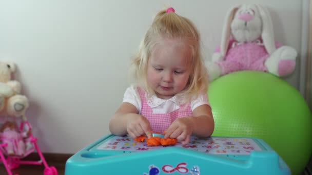 Childrens creativiteit. Kind meisje beeldhouwt uit plasticine aan de tafel. — Stockvideo