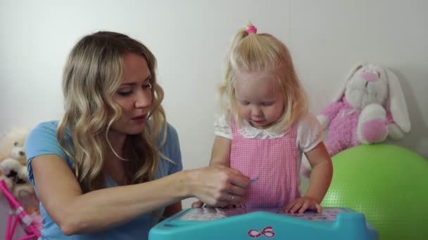 Vrouw en kind spelen aan de tafel in de kamer. Familie, moederschap. — Stockvideo