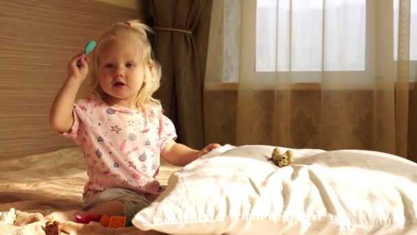 Bébé fille blonde jouant sur le lit dans la chambre . — Video