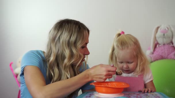 子供は、いたずらな少女金髪で食べたくないです。ママがスプーンで赤ちゃんをフィードします。. — ストック動画