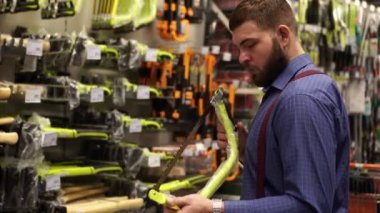 Sakallı adam el ile aracı bir donanım mağazasında seçer..