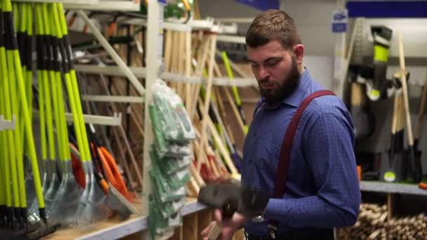 Hombre comprador en la ferretería elige una pala . — Vídeos de Stock