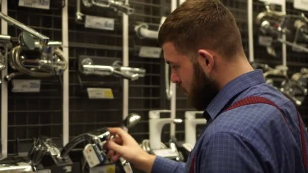 Un homme dans une quincaillerie choisit la plomberie et un robinet . — Video