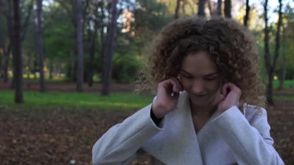 Mooie jonge vrouw in een jas in het park voorjaarsbijeenkomst. — Stockvideo