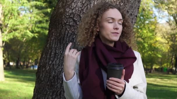 Affärskvinna som dricker kaffe i parken våren. — Stockvideo