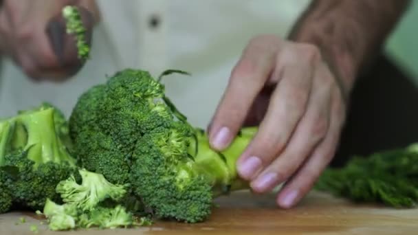 Um homem corta brócolos na cozinha. Vegetariano, comida saudável . — Vídeo de Stock