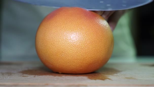 Een man snijdt een grapefruit. Man snijdt fruit. — Stockvideo