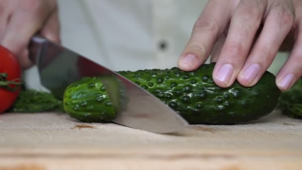 Um homem corta um pepino. Homem corta vegetais na cozinha . — Vídeo de Stock