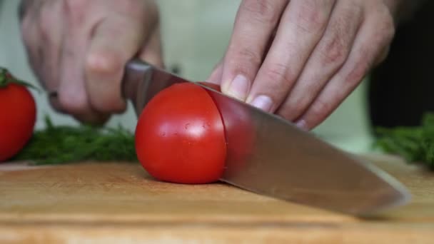 남자는 토마토를 잘라냅니다. 남자는 부엌에 야채 인하. — 비디오