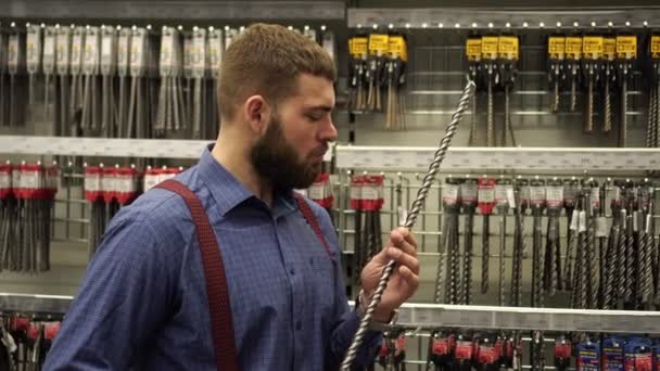 Uomo brutale in un negozio di ferramenta sceglie trapani . — Video Stock