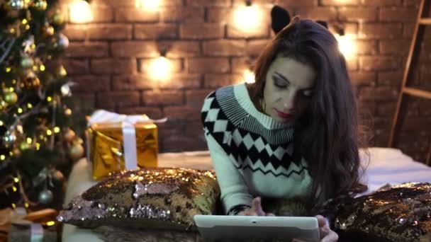 Mujer joven con tableta en el fondo del árbol de Navidad . — Vídeo de stock