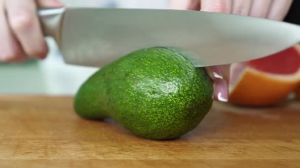 Frau schneidet Avocado in der Küche. — Stockvideo