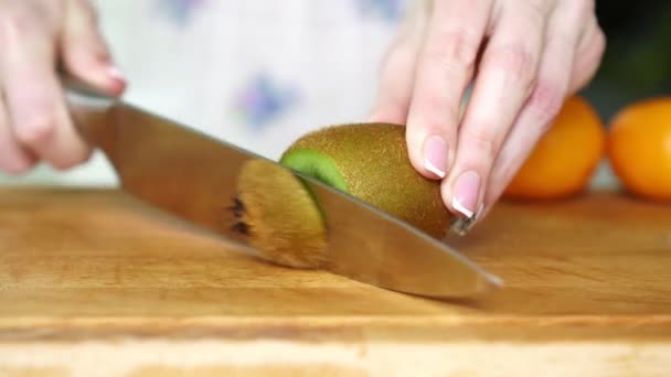 Eine Frau schneidet ein Messer Kiwi in der Küche, Nahaufnahme. — Stockvideo