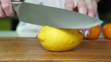 Bir kadın bir limon mutfakta bir bıçakla keser.