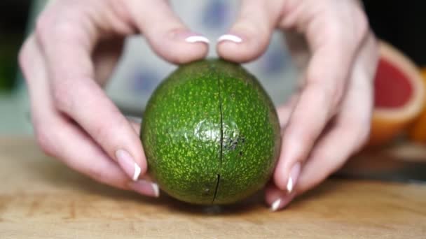 Женщина разрезает зелёный авокадо пополам . — стоковое видео