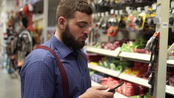 Mann im Baumarkt wählt Werkzeug. — Stockvideo