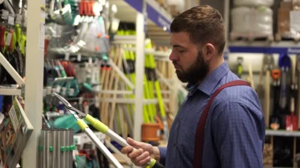 Een volwassen man in een ijzerhandel kiest hulpmiddelen. — Stockvideo