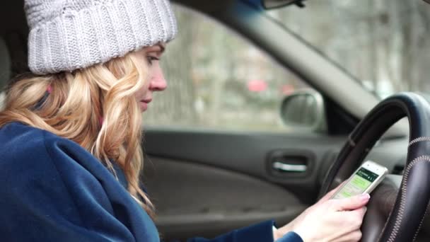 Eine junge Frau sendet eine Nachricht per Smartphone im Auto. — Stockvideo
