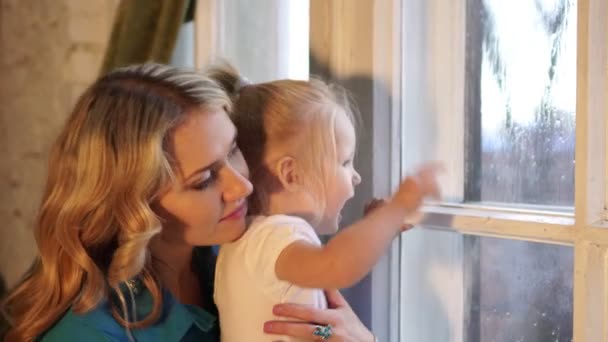 Otoño, lluvia, una mujer con un niño mirando por la ventana . — Vídeos de Stock