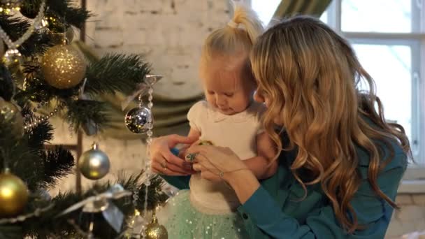 Una mujer con un niño decora el árbol de Navidad . — Vídeo de stock