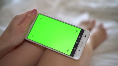 Bir smartphone ile yeşil bir ekran tutan kadın yakın çekim.