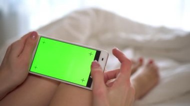 Kadın evde bir smartphone yeşil bir ekran ile tutarak.