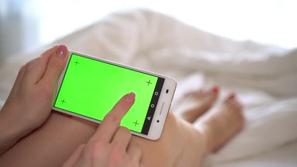 Vrouw op zoek naar slimme telefoon telefoon met groen scherm. — Stockvideo