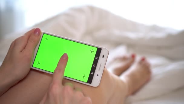 Close-up van een dames hand met een mobiele telefoon met een groen scherm. — Stockvideo