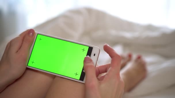 Kvinna hemma håller en smartphone med en grön skärm. — Stockvideo