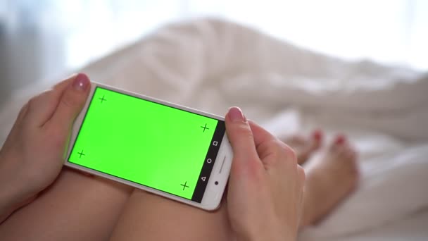 Mujeres manos sosteniendo un teléfono inteligente con una pantalla verde en blanco, primer plano . — Vídeos de Stock