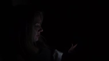 Bir kadın gece karanlıkta bir akıllı telefon kullanır.