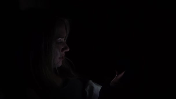 Uma mulher usa um smartphone à noite no escuro . — Vídeo de Stock