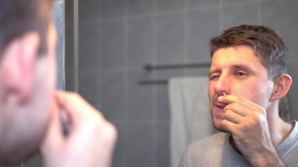 Mann zupft sich im Badezimmer mit Pinzette die Nasenhaare. — Stockvideo