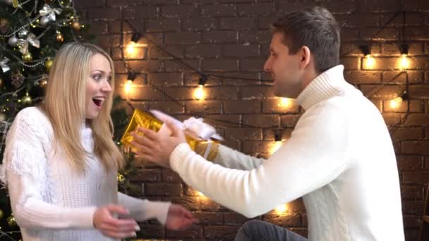 En man ger en kvinna en julklapp. — Stockvideo