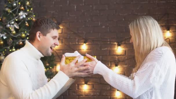 Um jovem casal dar uns aos outros presentes de Natal . — Vídeo de Stock