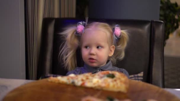 Ένα μικρό κορίτσι, τρώγοντας πίτσα σε ένα καφέ. — Αρχείο Βίντεο