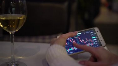 Bir kişi bir akıllı telefon üzerinde bir uygulama kullanarak borsada çalışır.