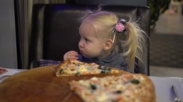 Dziecko dziewczynka jedzenie pizzy w kawiarni. — Wideo stockowe
