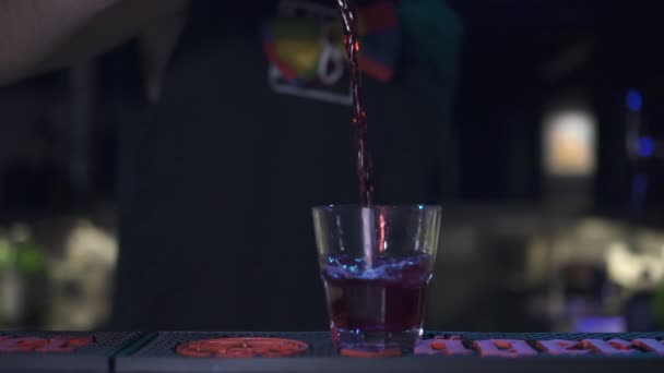 Μπάρμαν κάνει ένα κοκτέιλ. Χυμός που διοχετεύονται σε ένα ποτήρι με πάγο σε αργή κίνηση. — Αρχείο Βίντεο