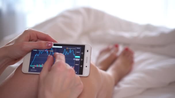 Una mujer mira los datos de la bolsa de valores en el grifo del teléfono inteligente, primer plano . — Vídeos de Stock