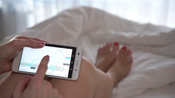 Borsa app üstünde onun smartphone kullanarak bir kadın çalışıyor. — Stok video