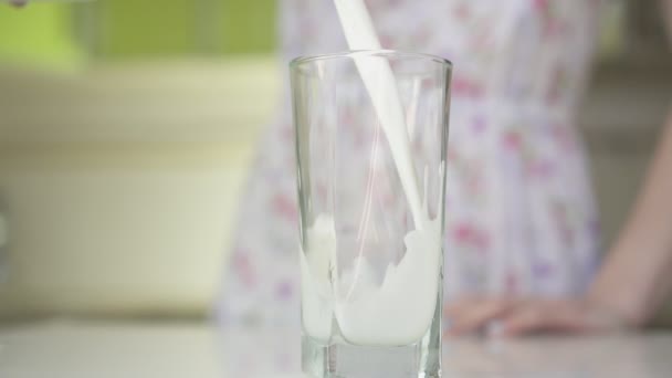 Vrouw in de keuken gieten melk in een glas. — Stockvideo