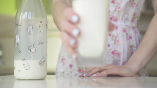 Femme met sur la table un verre de lait, au ralenti .