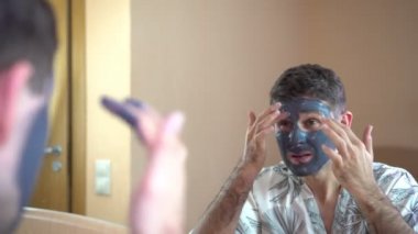 Bir adam bir yüz kozmetik kil maskesi koyar.