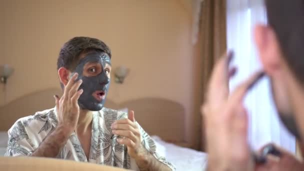 Ein Mann benutzt eine Gesichtsmaskencreme. Männerschönheit, Hautpflege. — Stockvideo