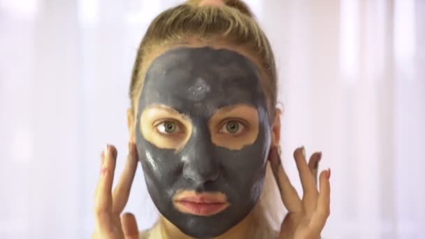 Retrato de una mujer con crema o máscara cosmética en la cara . — Vídeos de Stock