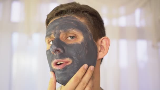 Porträt eines Mannes mit einer Creme- oder Tonmaske im Gesicht. — Stockvideo